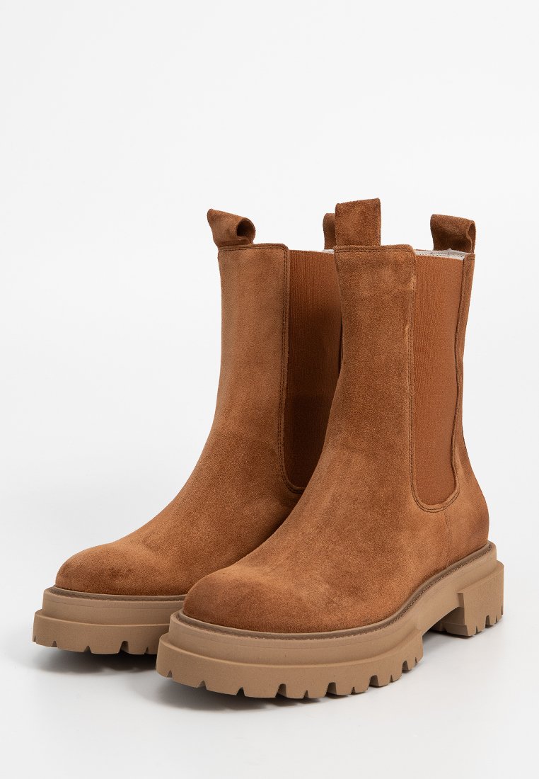 Ein Paar braune Wildleder Chelsea-Stiefel mit robusten Gummisohlen und elastischen Seiteneinsätzen für ein einfaches Hineinschlüpfen.