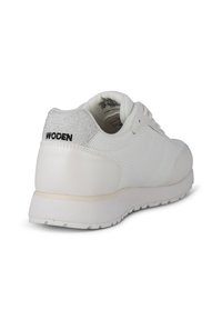 Zapatilla blanca con un panel trasero texturizado, un diseño frontal liso, parte superior de malla transpirable y costuras en contraste sobre una suela ligera.