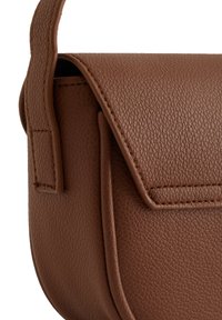 Brun läderväska med en texturerad yta, som har ett lockstängning, sidostygn och en rundad bottenkant. Kompakt design.