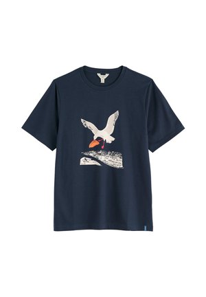 Marineblauw T-shirt met een witte vogel die een oranje vis vasthoudt boven een getextureerde zwart-witte vorm met tekst aan de voorkant.