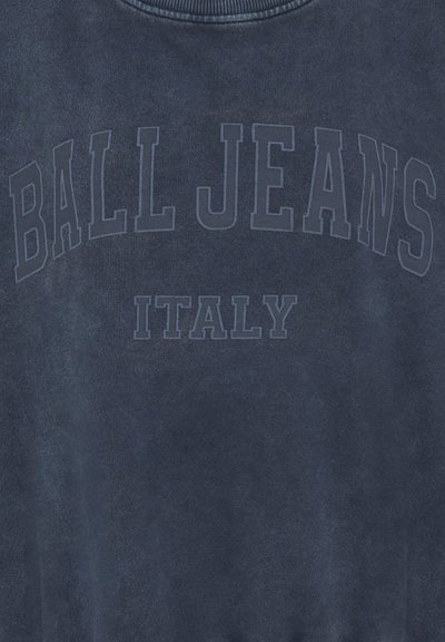 Tissu gris foncé avec un texte gris plus foncé délavé « BALL JEANS » courbé au-dessus de « ITALY » en lettres majuscules.