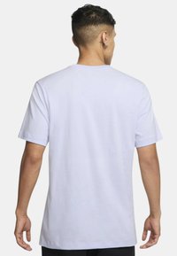 Camiseta de algodón blanca con un corte relajado, mangas cortas y cuello redondo. Textura suave, sin patrones ni gráficos visibles.