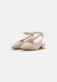 Zapatos slingback de gamuza beige con punta afilada, correa ajustable en el tobillo y un tacón medio con un acento dorado y perlas blancas.