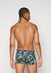 Schwarze Boxershorts mit einem tropischen Pflanzenmuster in Grün- und Rosatönen; der elastische Taillenbund trägt das Branding "JACK & JONES".