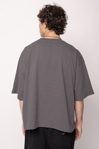 Šedé oversized tričko vyrobené z bavlny, s krátkými rukávy, kulatým výstřihem a hladkým zadním dílem bez grafiky nebo vzorů.