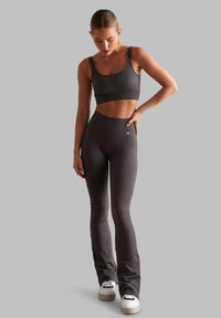 Bralette sportivo grigio a coste abbinato a leggings a vita alta, con un design aderente e tessuto testurizzato. Sneakers bianche completano l'outfit.