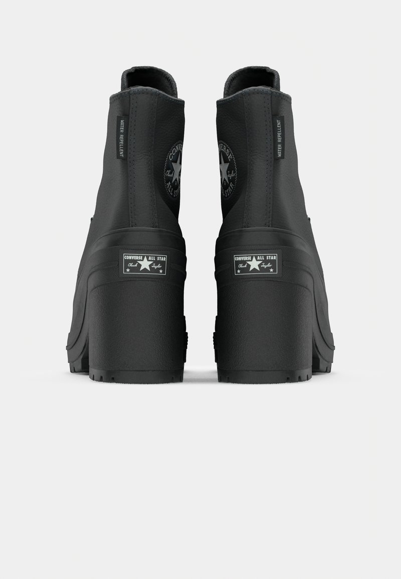 Bottines noires imperméables à talon plateforme épais, avec un bout arrondi et un détail de logo circulaire à l'arrière.