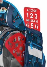 Sac à dos bleu et gris avec un extérieur à motifs, une teinture rouge et une tirette bleue. Inclut une planche avec des lettres et des chiffres.