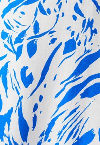 Blue and white fabric displaying an abstract pattern with bold, curved lines and organic shapes. The texture appears smooth and woven.