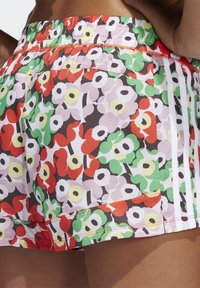 Bermudas florales multicolores con una mezcla de patrones en rojo, verde, rosa y negro. Cintura elástica con rayas de acento y tela texturizada.