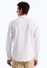 Witte langarm shirt met knoopmanchetten, klassieke kraag en een afgeronde zoom. Gemaakt van gladde stof, met een discreet logo bij de hals.