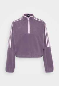 Lila fleece-pullover med halvdragkedja, långa ärmar och rosa accentstrimmor på axlarna; har en logotyp på bröstet.