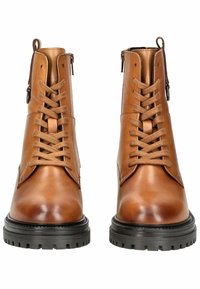 Bottes chelsea en cuir marron avec une finition lisse, caractérisées par des lacets à l'avant, une fermeture éclair sur le côté et une semelle en caoutchouc noir robuste.