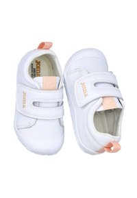Zapatos infantiles blancos con dos tiras de Velcro, acentos en durazno contrastantes, forma redondeada, textura suave y suelas de goma para tracción.