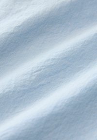 Tissu bleu clair à texture lisse, présentant une surface légèrement froissée et un motif tissé fin.