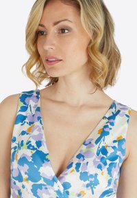 Blumenmusterkleid mit tiefem V-Ausschnitt, das in einem leichten Stoff in Blau-, Lila- und Orangetönen gestaltet ist. Weiche Textur und figurbetontes Design.