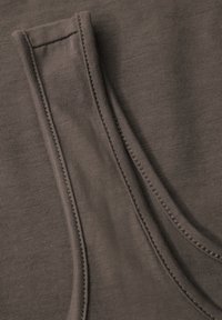 Tessuto a coste marrone con due cuciture laterali prominenti, caratterizzato da una superficie liscia e da una dettagliata cucitura lungo i bordi.