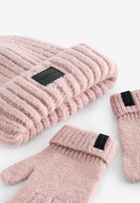Vaaleanpunaista ribbikudottua pipoa ja käsineitä sisältävä setti, jossa on teksturoitu kangas, taitettava reunus käsineissä ja mustat labelkoristeet.