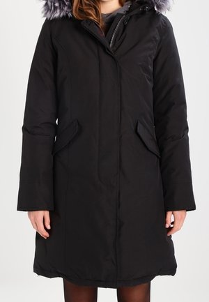 Sort parka med lynlås foran, to sidelommer, hætte med kunstpelskant og et struktureret, isoleret stof.