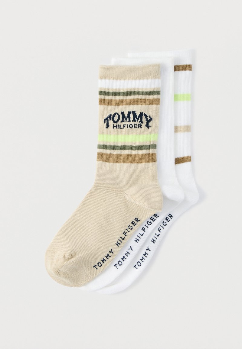 Trois paires de chaussettes Tommy Hilfiger : beige avec rayures et logo, blanches avec rayures marron, et blanches simples. Matière en coton, longueur mi-mollet.