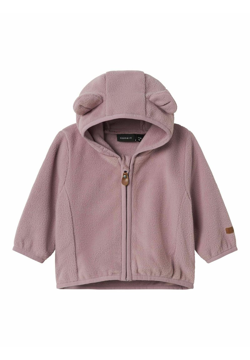Fleece bunda v jemnej fialovej farbe, so kapucňou s ušami medveďa, predným zipsom a štruktúrovaným povrchom. Doplnková kožená nášivka.