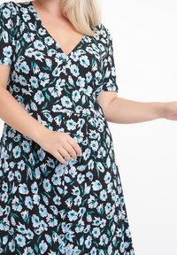 Robe noire à fleurs avec un col en V, manches courtes, présentant un motif floral bleu et vert, tissu doux et taille cintrée.