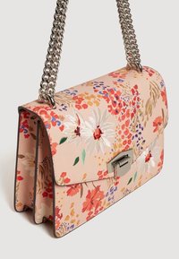 Sac à bandoulière à motif floral en matériau synthétique rose pâle, avec une chaîne en argent et un fermoir métallique. Surface texturée et broderie détaillée.