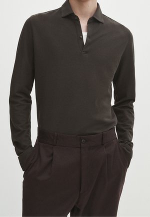 Dark brown long-sleeve polo shirt with a buttoned collar, paired with dark trousers featuring a flat front and side pockets.