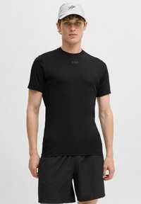 Schwarzes, kurzärmeliges Sportshirt mit Rundhalsausschnitt und taillierter Passform, kombiniert mit schwarzen Shorts. Enthält den Text "CNZ" auf der Brust.
