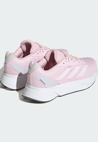 Różowe buty sportowe z siateczkową cholewką, wyściełanym językiem i białymi akcentami. Posiadają teksturowany wzór oraz wyściełaną białą podeszwę dla wsparcia.