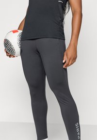 Fekete, slim fit sportleggings, fehér Párizs logóval az alsó lábszáron és sima, rugalmas anyaggal.