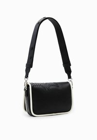 Borsa in pelle nera con una parte frontale testurizzata, bordo bianco e una tracolla staccabile con bottoni a pressione. Inclusi dettagli in metallo argentato.