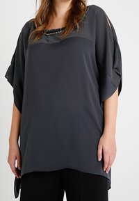 Ciemnoszara bluzka o luźnym kroju, z szerokimi r�ękawami i koralikowym dekoltem. Miękka, jedwabista w dotyku, z zaokrąglonym dolnym brzegiem.