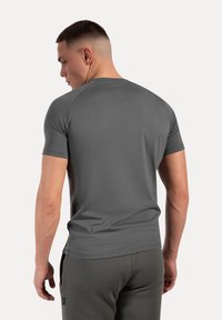 Grijs aansluitend T-shirt met korte mouwen, met een zachte textuur en een ronde halslijn, van achteren weergegeven, gecombineerd met donkergrijze broek.