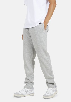Grijze joggingbroek van een katoenmengsel, met een relaxte pasvorm, zijzakken en een elastische band aan de enkels, gecombineerd met witte sneakers.