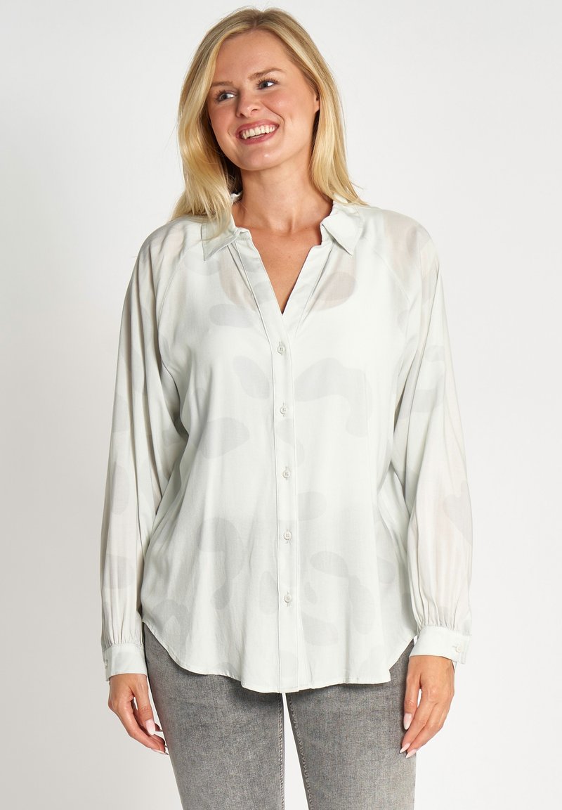 Light green, long-sleeved blouse with a button-down front, featuring a subtle abstract pattern and soft, smooth fabric.