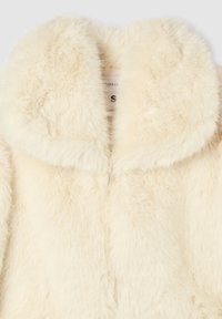 Cappotto in pelliccia sintetica color crema con ampio colletto, caratterizzato da una texture morbida e soffice e un design semplice e chiuso. L'etichetta indica la taglia 'S.'