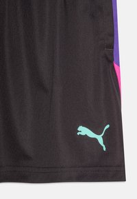 Čierne športové šortky s fialovými a ružovými bočnými panelmi. Obsahujú svetlo modré logo Puma blízko lemu. Vyrobené z hladkej tkaniny.