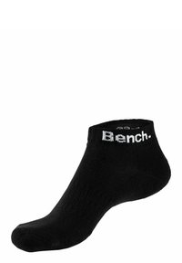 Schwarze Knöchelsocke aus einem weichen Stoff, mit einer gerippten Textur und einem weißen "Bench."-Logo am Bund. Einfaches, minimalistisches Design.
