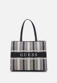 Tygväska i beige och marinblått med randigt mönster, slät tyg och svart logoband. Inkluderar två stadiga handtag för bärning.