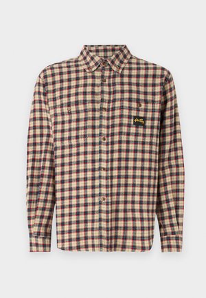 Chemise en flanelle à carreaux beige, rouge et bleu marine. Dotée de deux poches poitrine, d'une fermeture à boutons et d'un petit patch logo. Manches longues avec poignets à bouton.