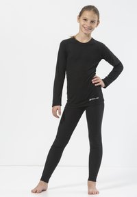 Svart termisk långärmad topp och leggings, ribbad textur, figurnära design, med en liten logotyp på höften, bärs utan skor.