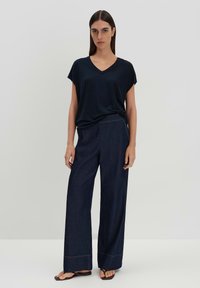 T-shirt navy a scollo a V con maniche corte abbinato a jeans in denim scuro a vita alta e gamba larga con cuciture visibili e sandali piatti.