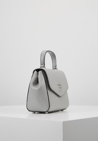 Szara torebka z materiału imitującego skórę, o wyraźnie ukształtowanym kształcie, z górnym uchwytem i magnetycznym zapięciem na klapę. Posiada ozdobne przeszycia i metalowe okucia.