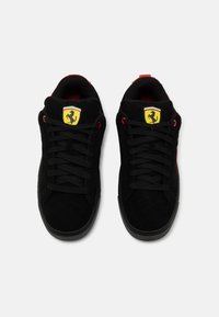 Melnas zamšādas kedas ar izquiltotu tekstūru, sarkaniem akcentiem un melnām auklām. Uz mēles redzams dzeltenais Ferrari logo. Gumijas zole.