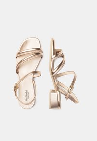 Sandali metallici dorati con molteplici cinturini incrociati, punta quadrata e tacco a blocco. Include una fibbia laterale per una vestibilità regolabile.