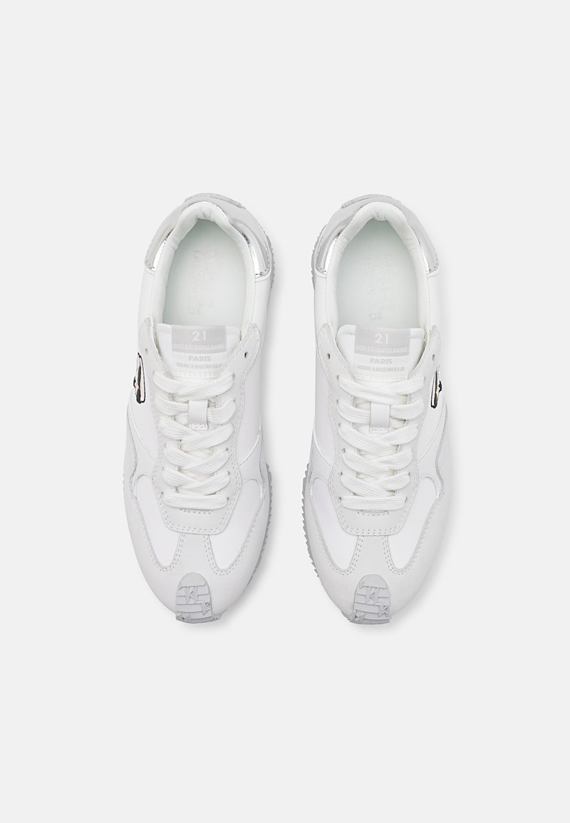 Pareja de zapatillas blancas con cordones y detalles en gris, vistas desde arriba, mostrando los logotipos en las lenguas y los paneles laterales.