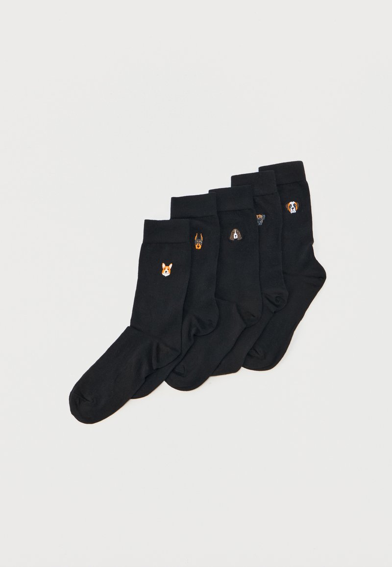 Cinq paires de chaussettes noires disposées côte à côte, chacune avec un petit visage de chien brodé différent près du bord-côte.