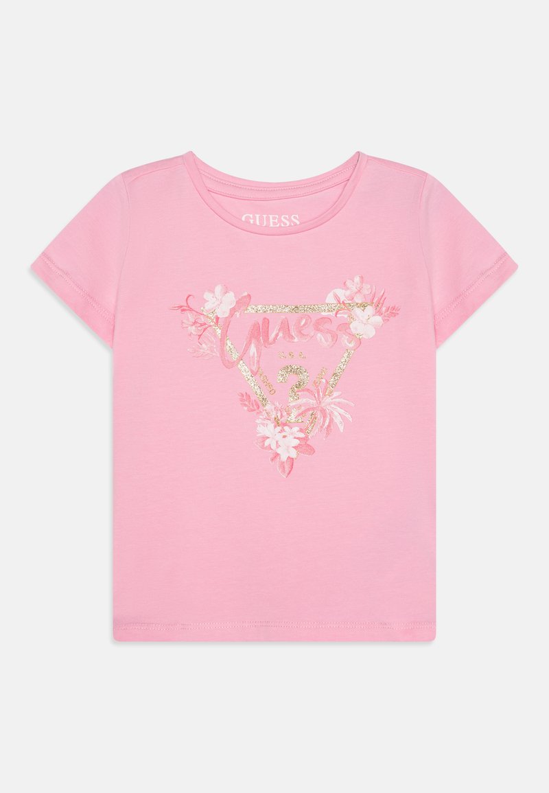 Rózsaszín pamut póló, virágos mintával és csillogó arany "GUESS" logóval egy háromszögben. Rövid ujjú és kerek nyakú.