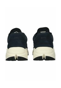 Navy suede urheilukengät, joissa on kerma- ja musta kumipohja. Varustettu pehmustetulla kauluksella ja teksturoiduilla yksityiskohdilla kantaosassa.